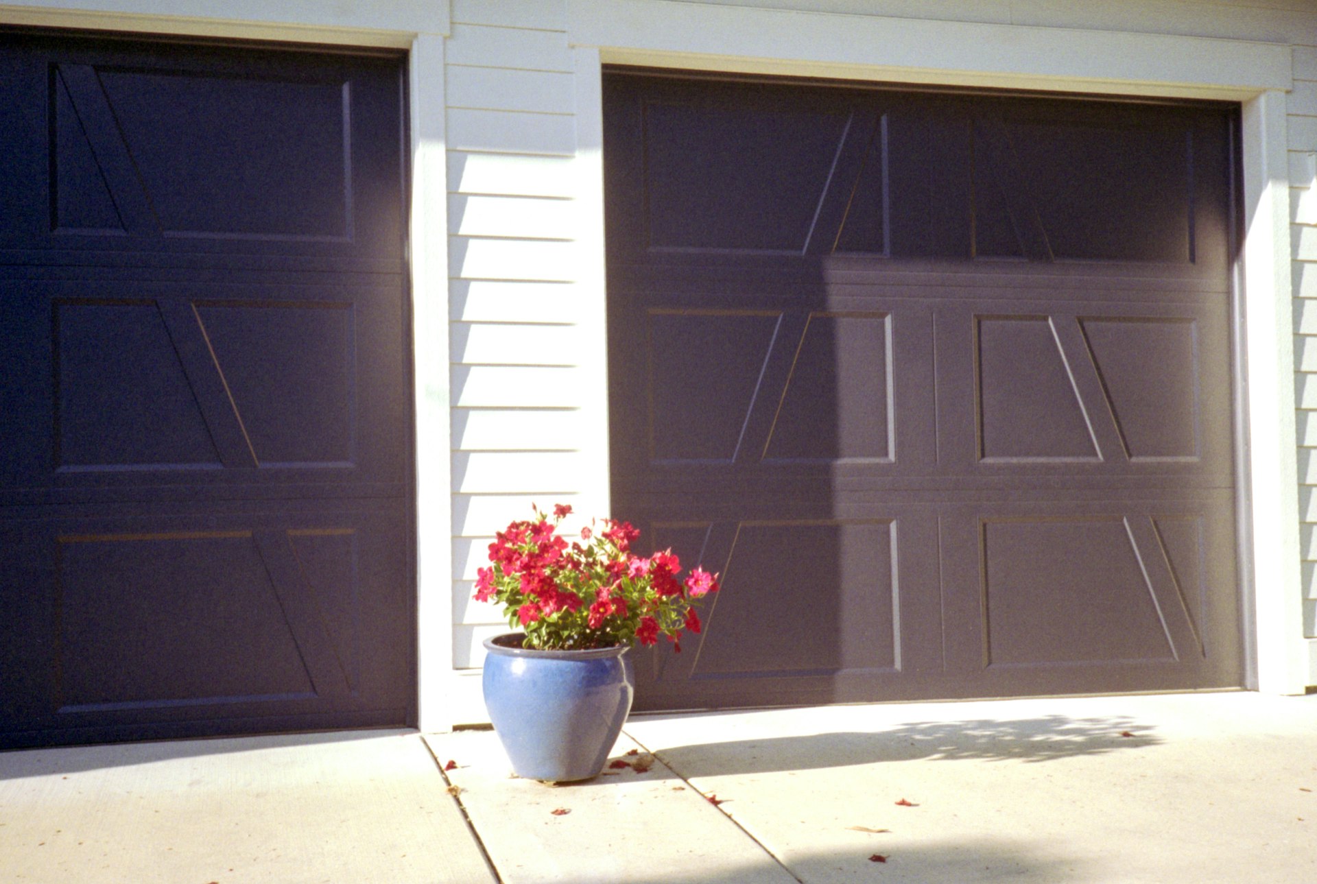 Two garage doors flank a pot of vibrant flowers.